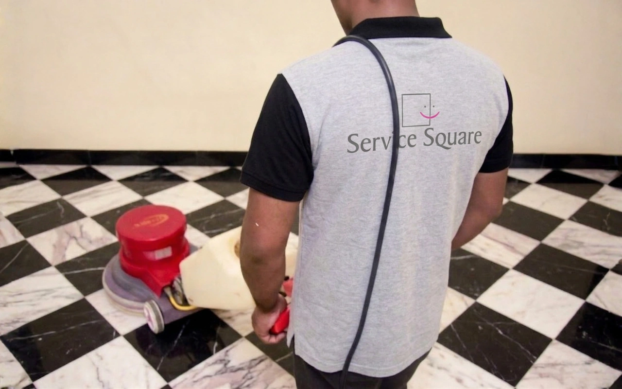 Service Square technician operating a rotary scrubbing machine on a black and white checkered marble floor in Chennai
