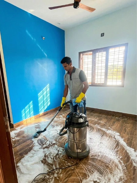 Service Square technician using an industrial wet-dry vacuum and rotary scrubber on tiled floor in an empty room in Chennai