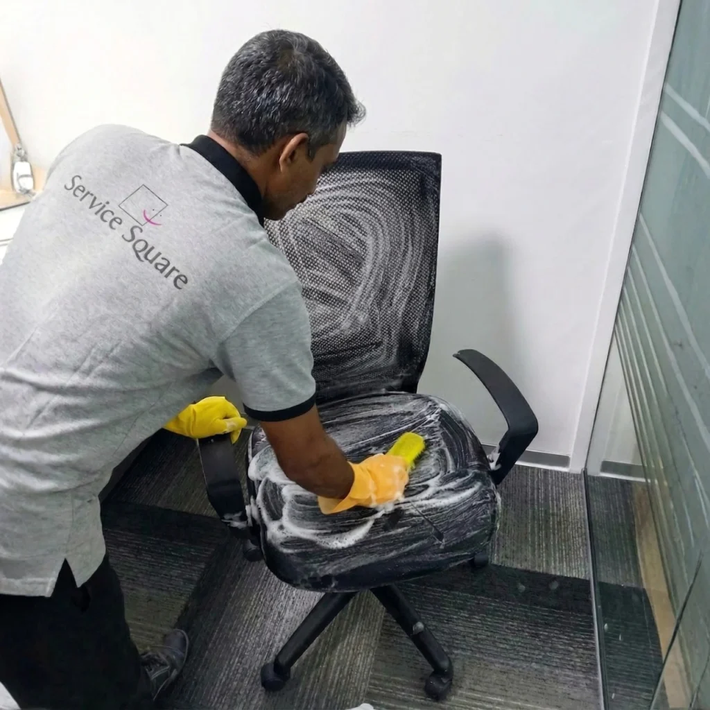 Service Square technician cleaning office mesh chair upholstery with foam and a sponge in Chennai